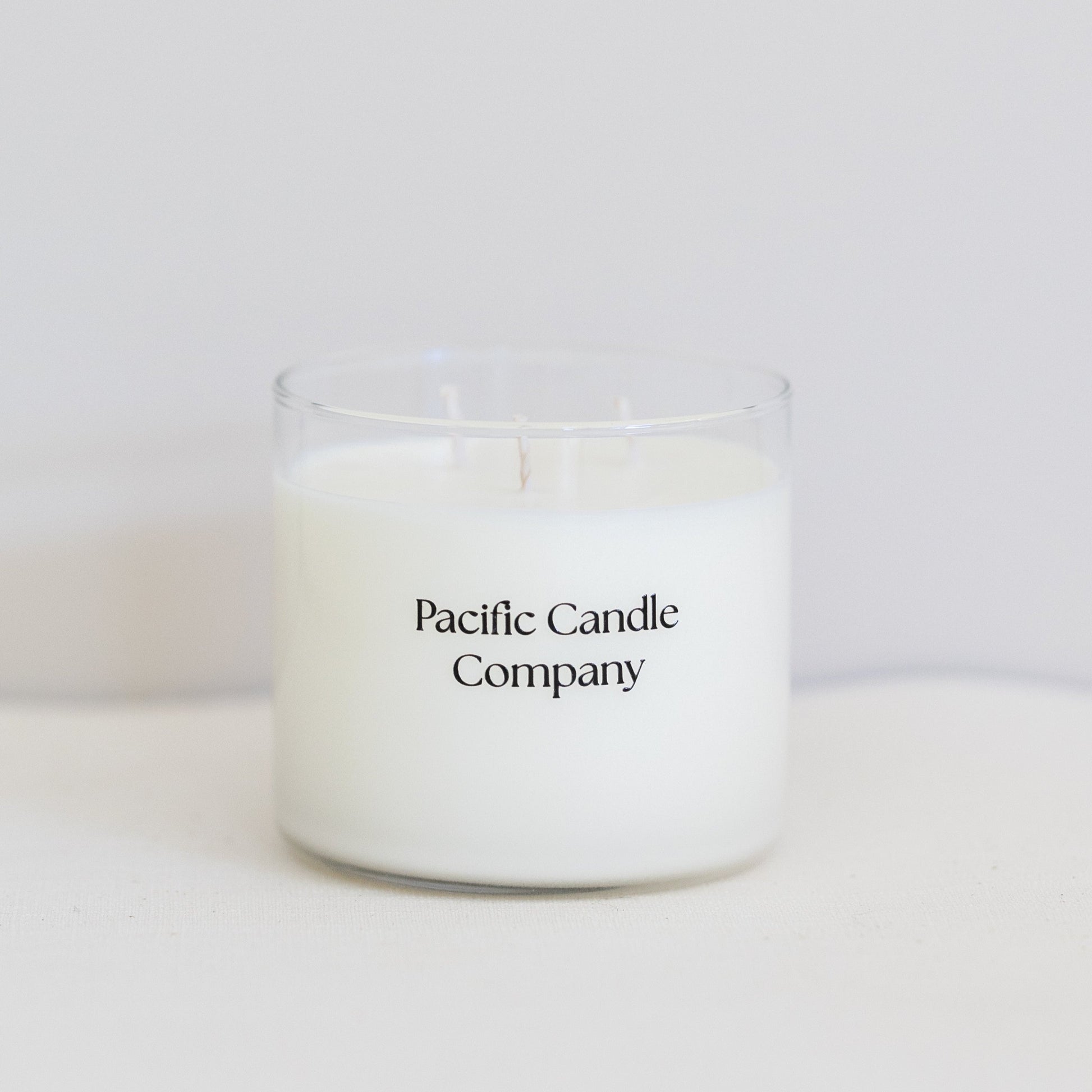 A luxurious triple wick soy candle in a wide, elegant glass vessel, crafted for a long-lasting burn and a bold, even scent throw. Designed to elevate the ambiance of larger spaces with its sophisticated look and fragrance. 